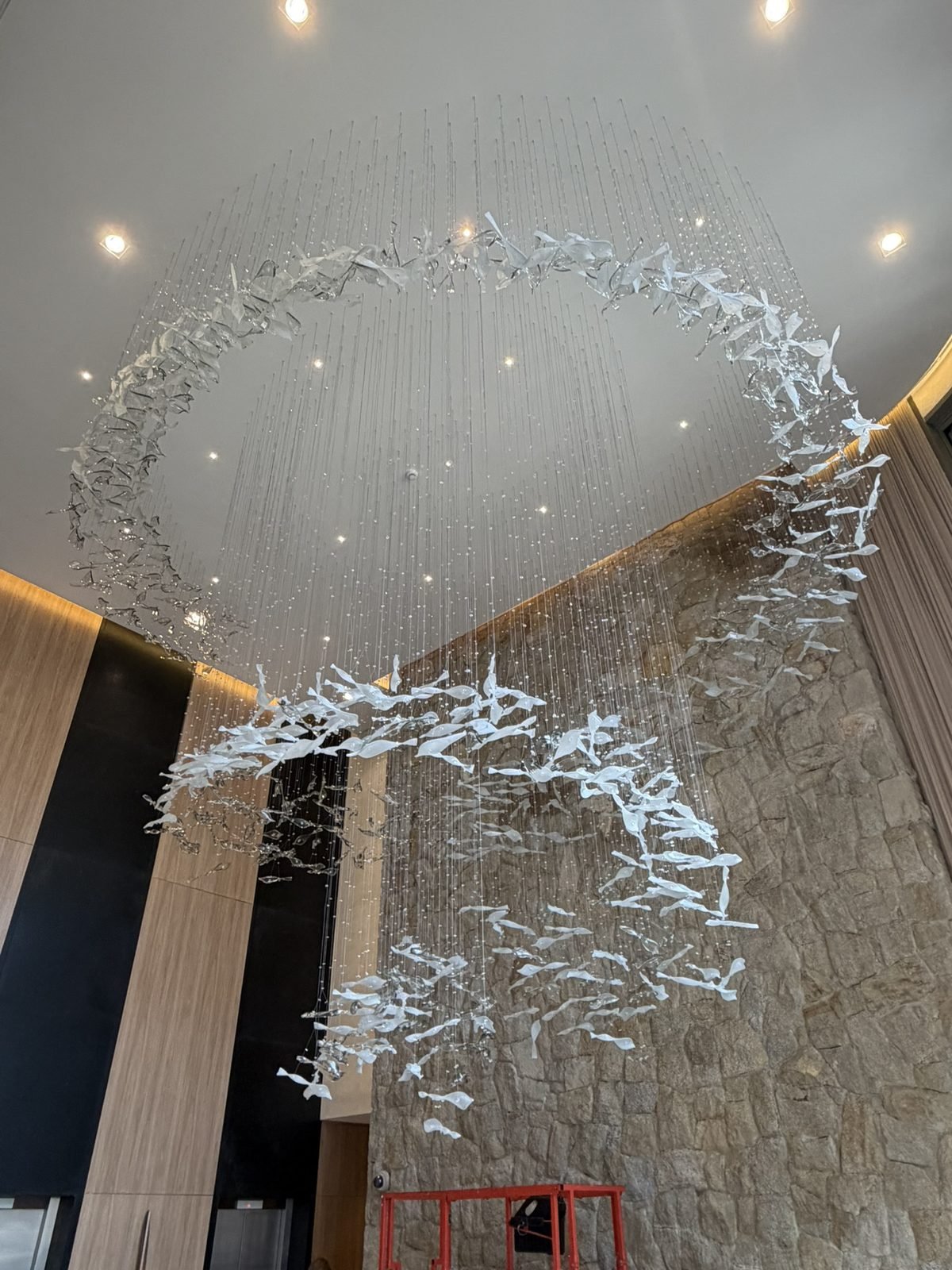Casa Ibirapuera Torre 3 — Espiral de Folhas e Cristal no Lobby — Vista geral da espiral com os painéis ripados em madeira ao fundo