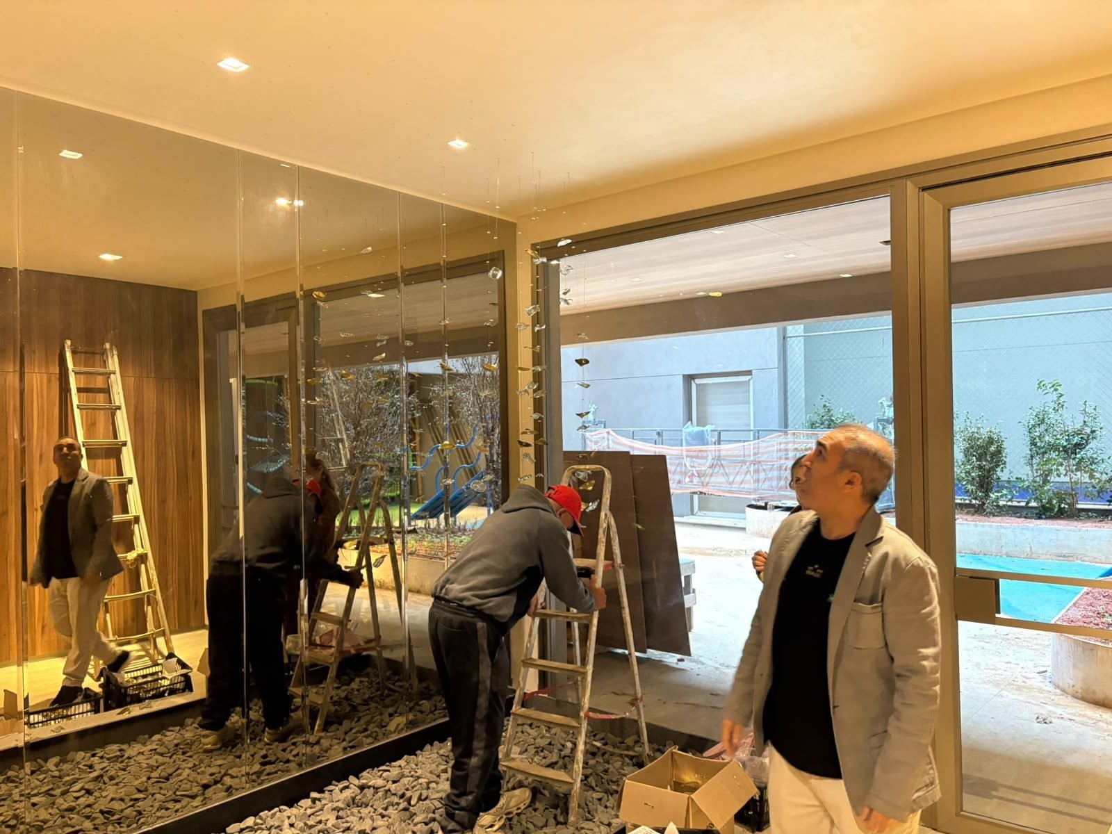 Casa Ibirapuera — Chuva de Cristal e Folhas Douradas — Detalhe da instalação junto ao painel de madeira
