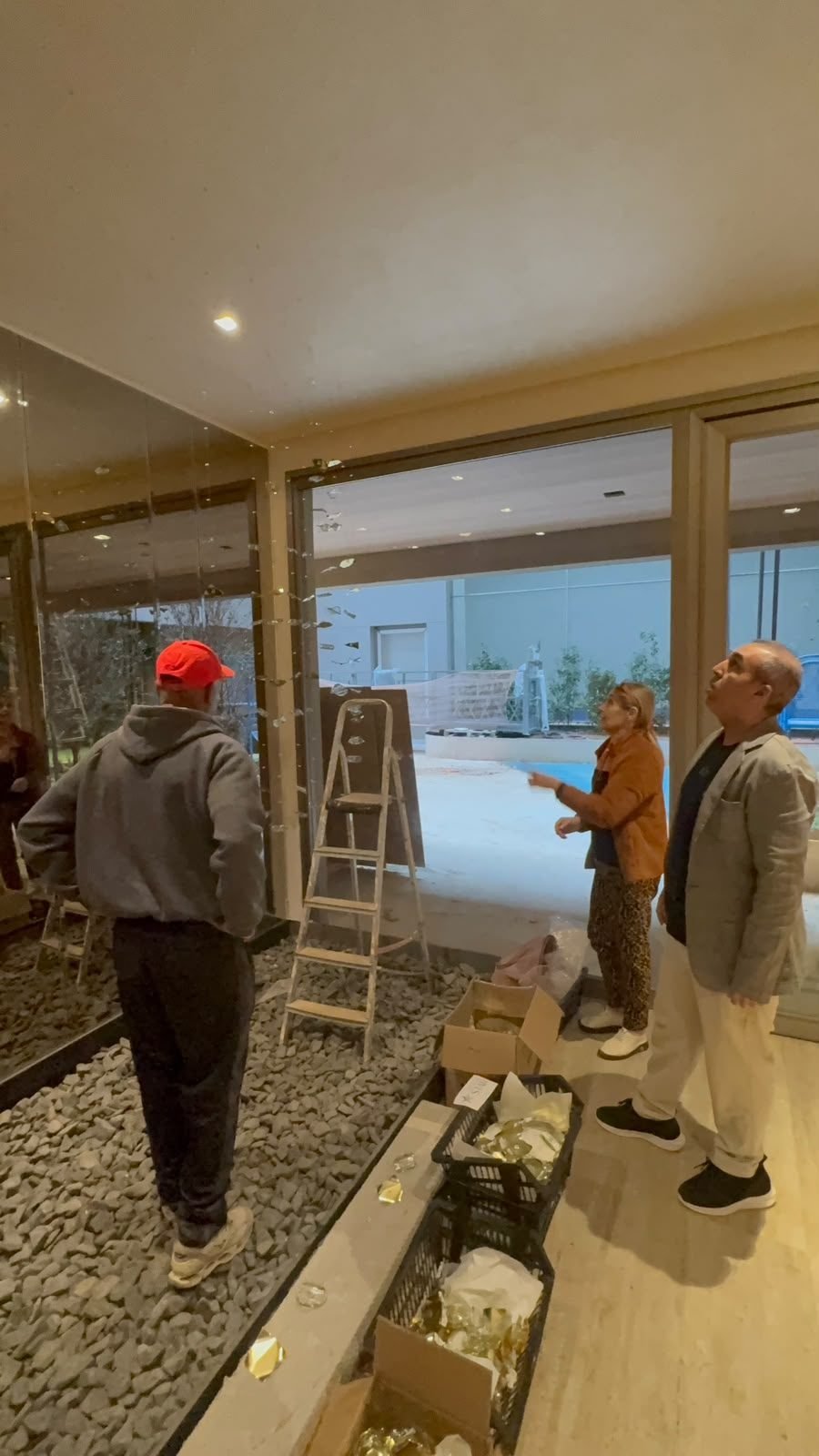 Casa Ibirapuera — Chuva de Cristal e Folhas Douradas — Equipe observando a peça no vão envidraçado