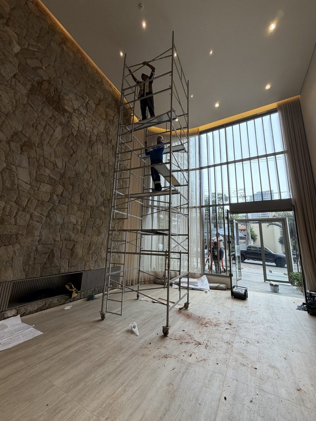 Casa Ibirapuera Torre 3 — Espiral de Folhas e Cristal no Lobby — Andaime no centro do átrio, com a fachada envidraçada ao fundo