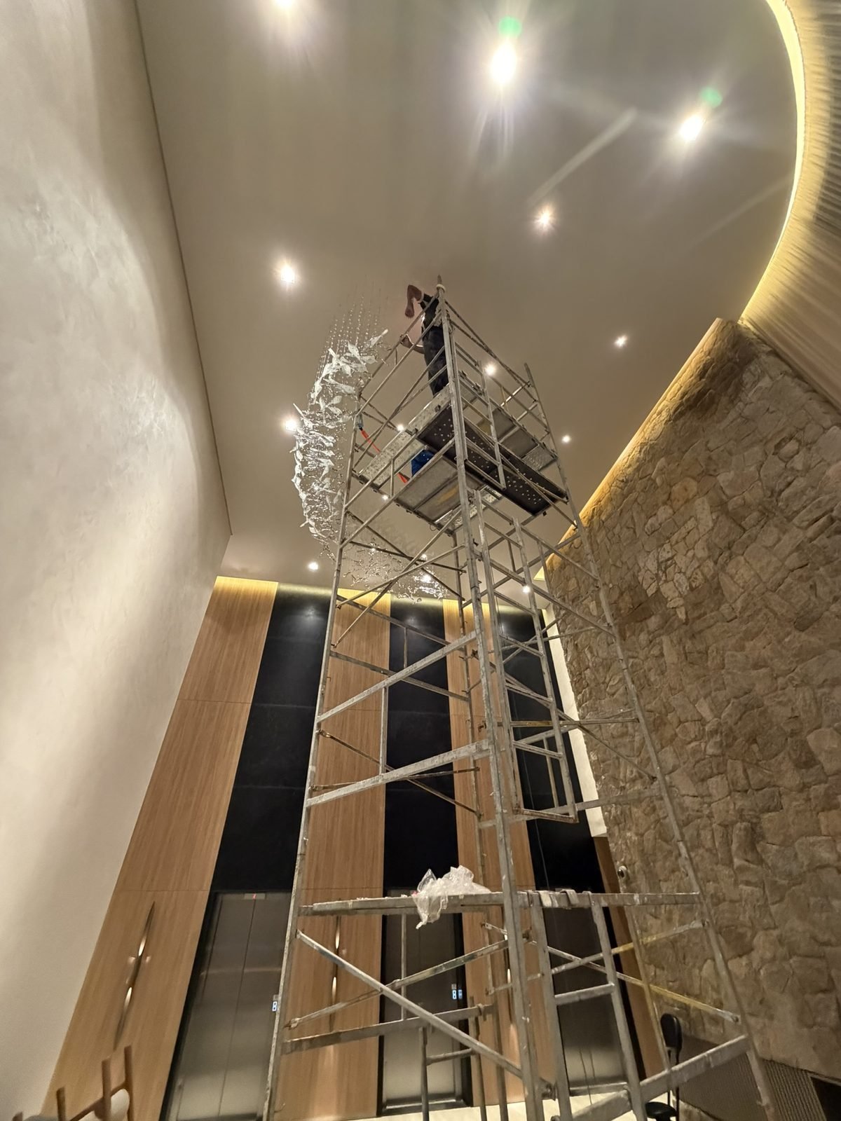 Casa Ibirapuera Torre 3 — Espiral de Folhas e Cristal no Lobby — Espiral descendo pelo átrio, vista junto ao painel ripado